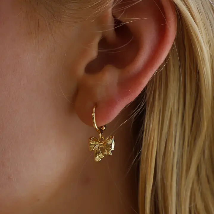 Beautiful huggies by Katie Waltman, this style is the Golden Bow Huggies. They feature Elegant Gold Huggie Earrings with Delicate Bow Design.  Dainty & Timeless Jewelry for a Feminine, Chic Look.