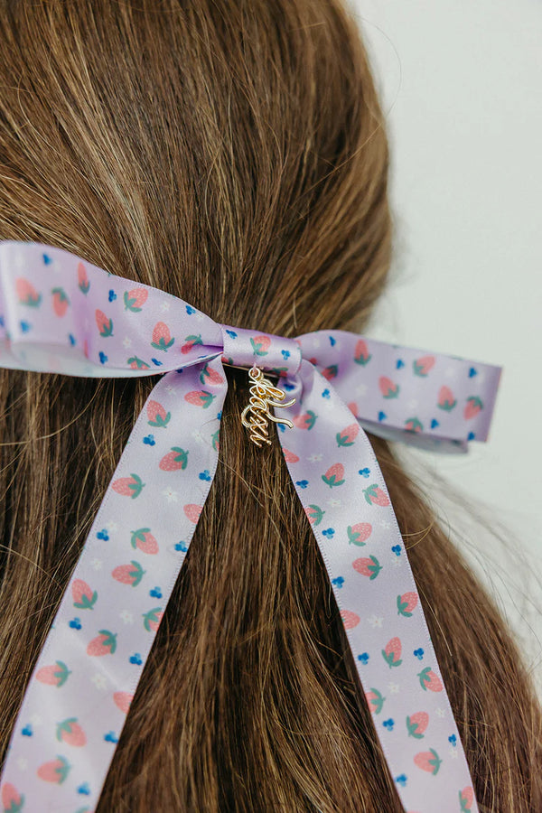 Jensen Arnold x KAXI Bow – Stylish, statement bow designed in collaboration with Jensen Arnold, perfect for elevating any hairstyle with elegance and flair. This tending bow features a beautiful pastel purple with little berries. 